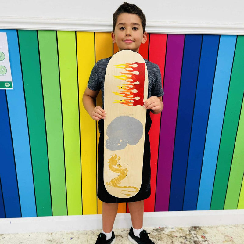 Child holding a skateboard from a skateboard deck party at DIY Invasion